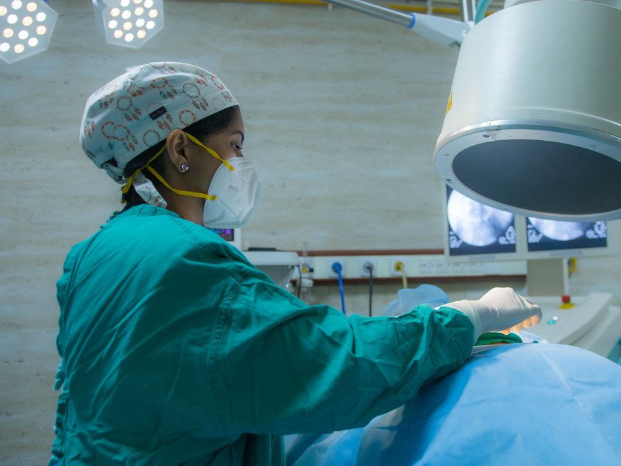 Dr. Kalpana K positioned at the operating table beneath the C-arm detector